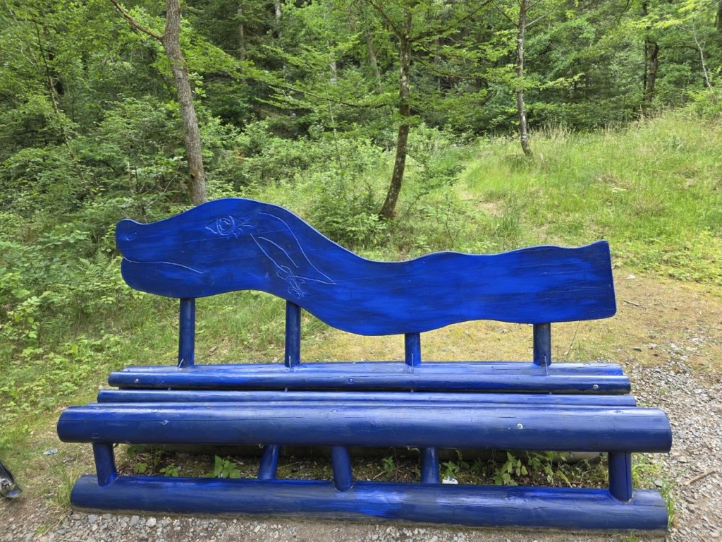Eine blaue Holzbank, die einen stilisierten Drachen darstellt.